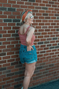 Side view of woman standing against brick wall