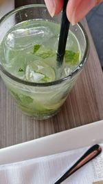 Close-up of hand holding drink on table