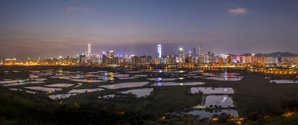 Illuminated buildings by city against sky at night