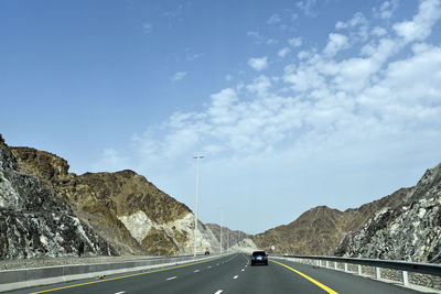 Cars on road by mountain against sky