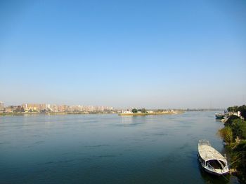 Scenic view of sea and buildings against clear blue sky