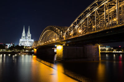 Illuminated bridge over river at night