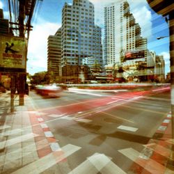 Blurred motion of vehicles on road against buildings in city