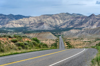 Road leading towards mountains against sky