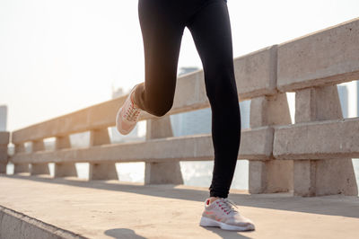 Low section of woman standing on footpath