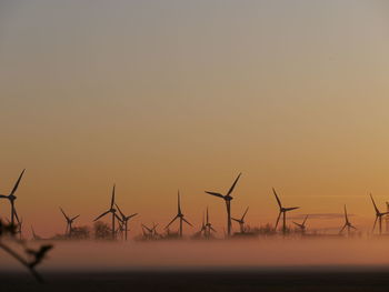 Silhouette of wind turbine against sky during sunset