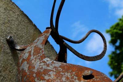 Low angle view of rusty metallic structure against blue sky