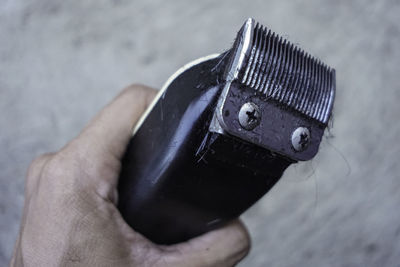 Cropped hand of man holding electric razor with hairs