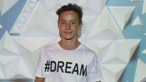 Light falling on happy teenage boy wearing t-shirt with dream text