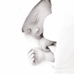 Close-up of father holding baby hand against white background