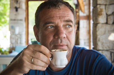 Thoughtful mature man drinking coffee at cafe