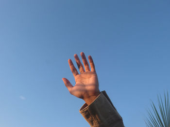 Low angle view of person hand against sky