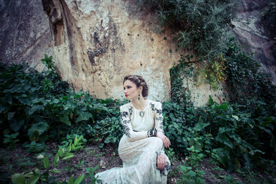 Portrait of a young woman standing against plants
