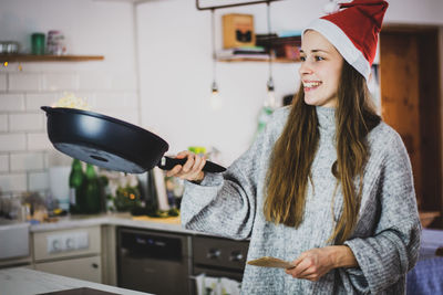 Portrait of young woman standing in kitchen