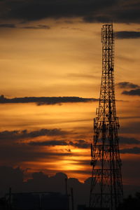 Low angle view of silhouette communications tower against sky during sunset