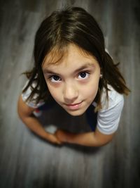 High angle portrait of cute girl crouching on floor