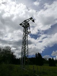 Low angle view of electricity pylon on field against sky