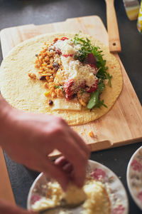 Close-up of hand holding pizza on cutting board