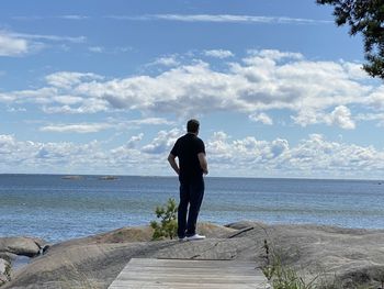 Rear view of man looking at sea against sky