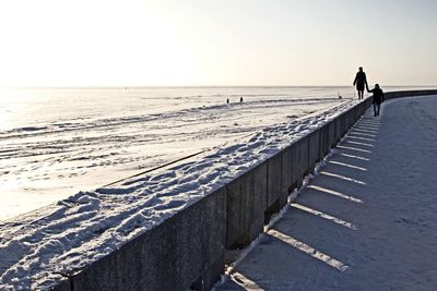 Man walking on beach against clear sky