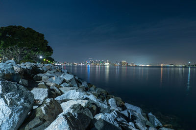 Illuminated rocks by sea against sky at night