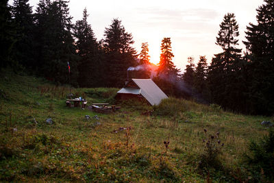 Tent in field against sky at sunset