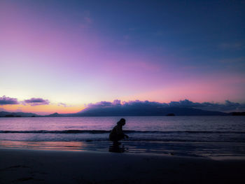 Silhouette man on beach against sky during sunset