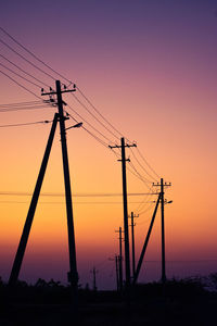 Silhouette electricity pylon against sky during sunset