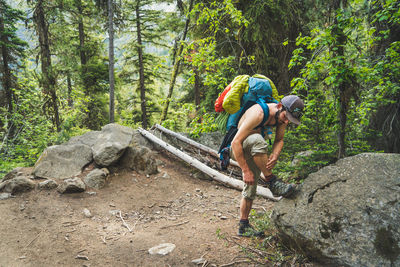 Man climbing on rock in forest