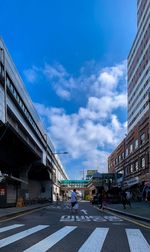 People walking on city street against sky