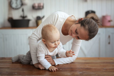Mom plays with the baby in a real interior, normal communication, the baby crawls.