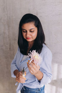 Woman of indian ethnicity using florist tools on a pastel colored flower