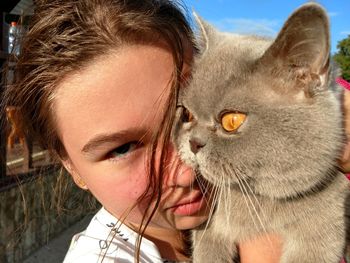 Portrait of teenage girl carrying british shorthair cat outdoors