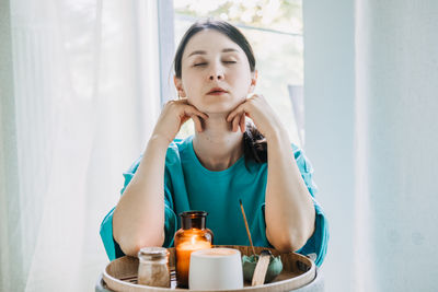 Portrait of smiling young woman drinking glass jar at home
