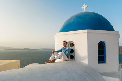 Man sitting on temple against sky