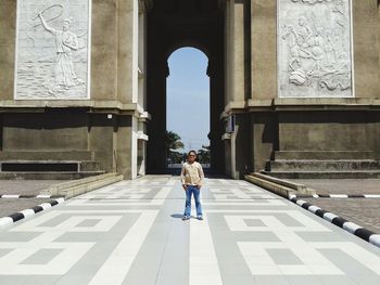 Full length of man standing on footpath against arch