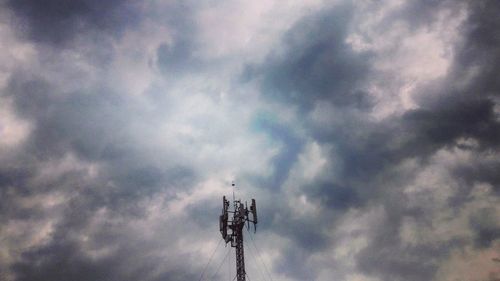 Low angle view of communications tower against cloudy sky