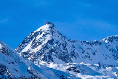 Scenic view of snow covered mountains against blue sky