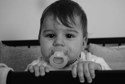 Close-up portrait of baby boy with pacifier in mouth at home