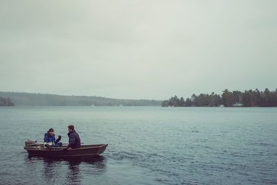 Men sitting in boat against sky