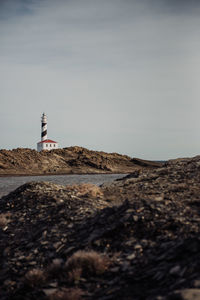 Lighthouse on beach against clear sky