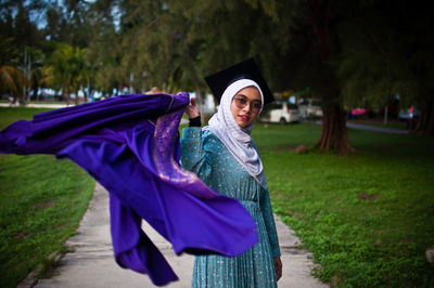 Portrait of smiling young woman standing against plants