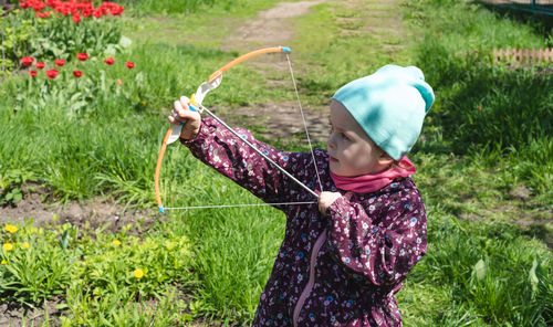 Child 4-year-old shoots up with a bow outside. side view.