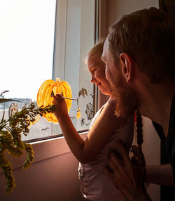 Child father painting pumpkin on window preparing halloween little girl dad drawing decorating room