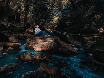 People sitting on rock in water