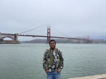 Portrait of smiling man standing on bridge against sky. golden gate bridge 