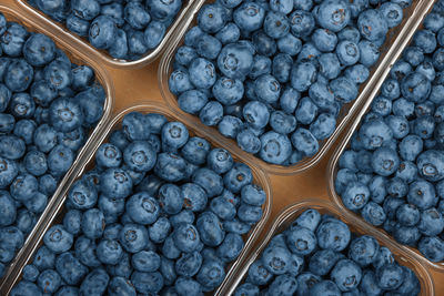 Close up several plastic containers of fresh ripe blueberry berries in brown cardboard box