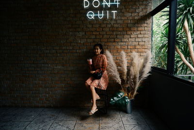 Full length of woman standing against wall