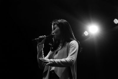 Low angle view of woman with microphone singing in concert