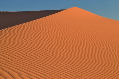 Low angle view of sand dunes against clear sky